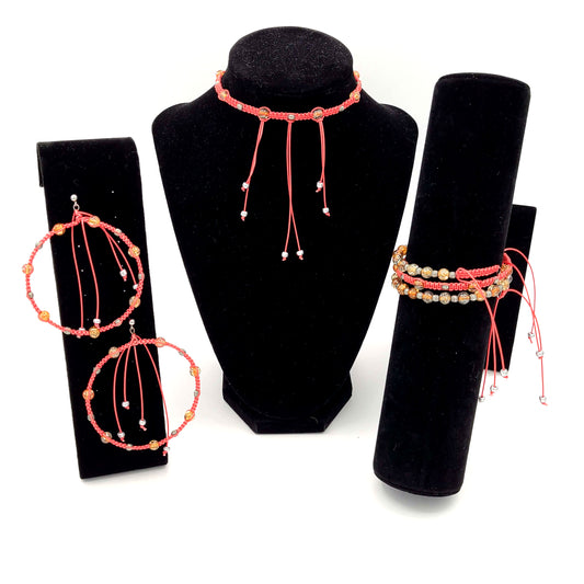 Jewelry set of red macrame earrings, bracelet and choker necklace on black velvet displays. 