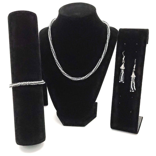 Three piece jewelry set of a necklace, earrings, and a bracelet / anklet, on black velvet display stands. They are made of black and light gray seed beads with silver colored earring wire, end caps, lobster clasps, and extender chains.