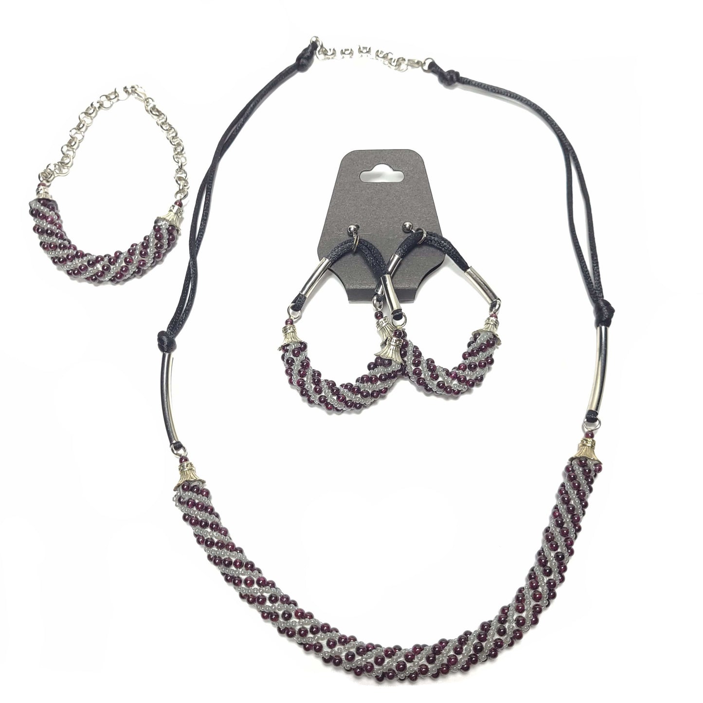 Jewelry set of a necklace, earrings, and a bracelet. They are composed of gray and amethyst beads in a Russian swirl pattern. The earrings and necklace have silver colored tubing and end caps. The earrings and necklace have black satiny cord. The bracelet has a silver colorado chain and clasp.