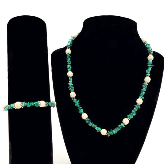 Necklace and earrings made of malachite chips and howlite beads with silver tone spacers on black display stands.