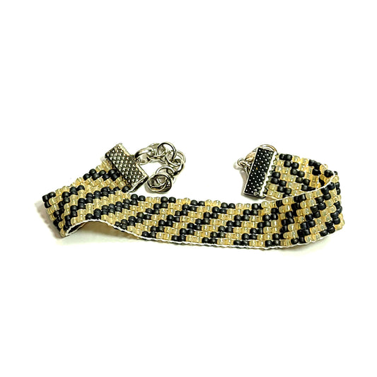 Classic looking unisex bracelet made with black and gold color seed beads with a diagonal striped pattern. It has an extender chain 