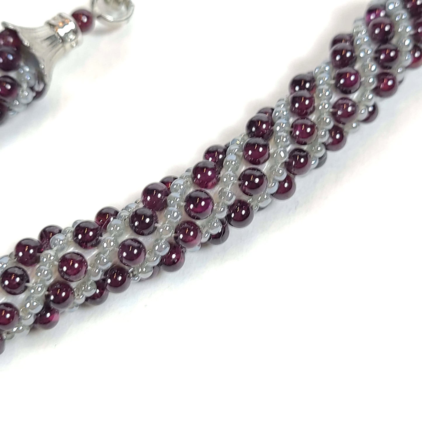 Close up view of necklace made of gray and amethyst beads in a Russian Swirl pattern.