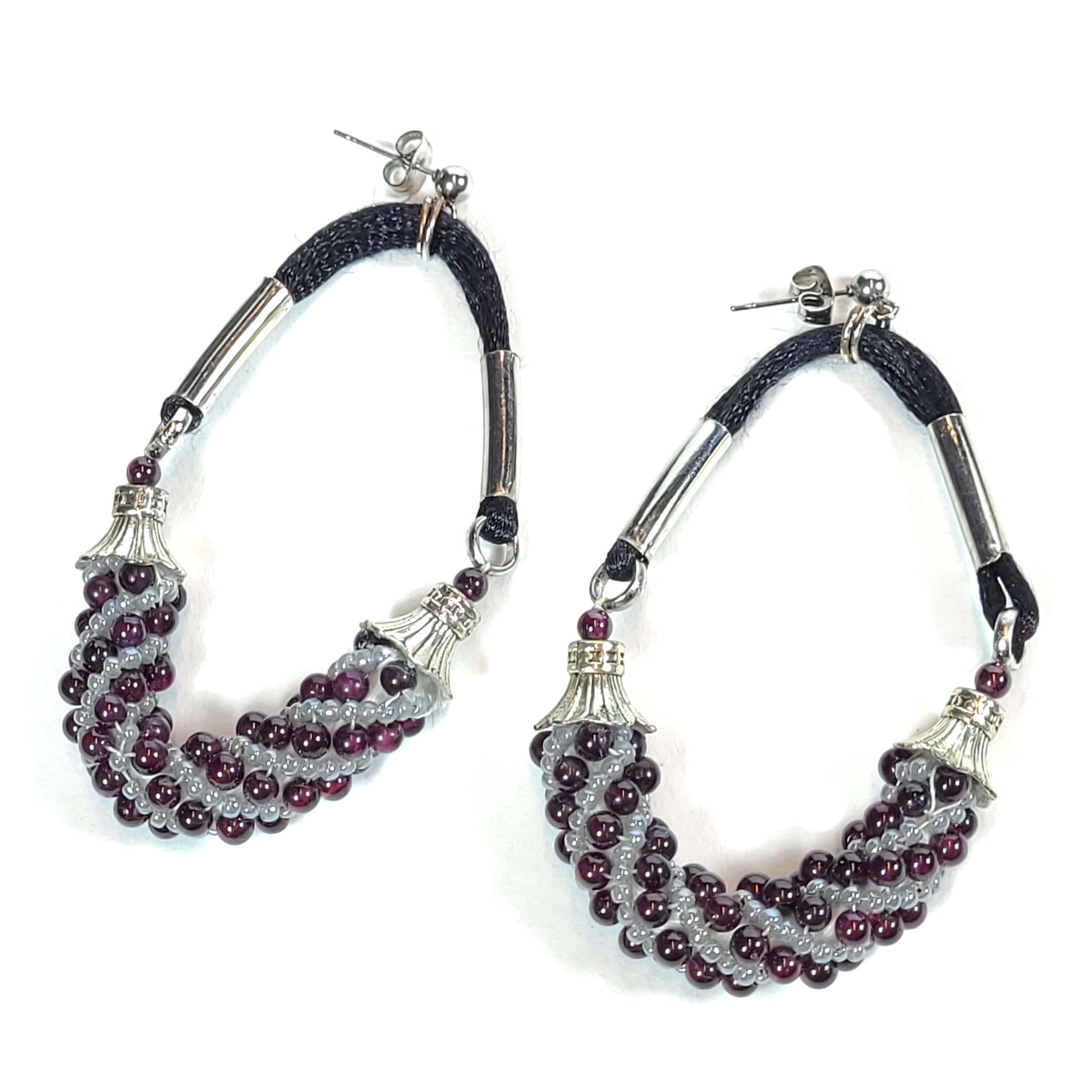 Hoop earrings made of gray and amethyst beads in a Russian swirl pattern. They have silver colored endcaps and tubes.They have black satiny cord.