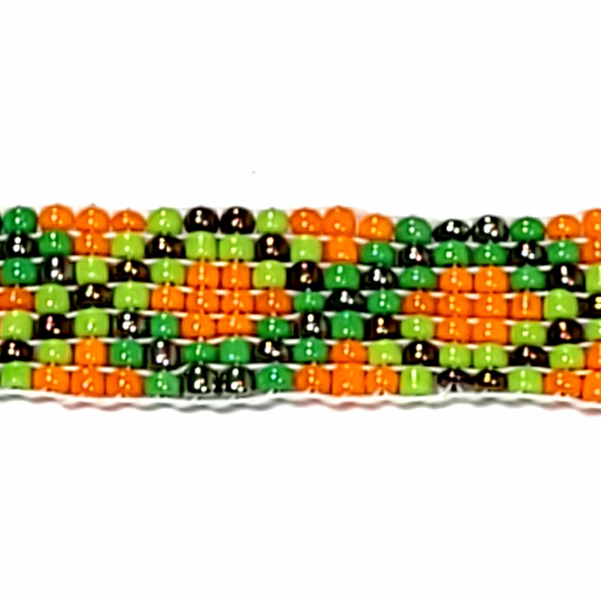 Close up view of woven seed bead bracelet with orange, green, and black beads. Has a cute bead with copper wire accent on the extender.