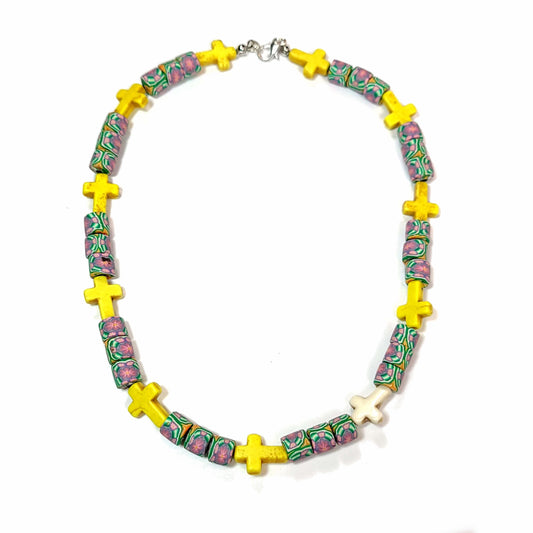 Polymer bead necklace with cylindrical beads that have a floral pattern, and 10 yellow crosses, and 1 white cross.