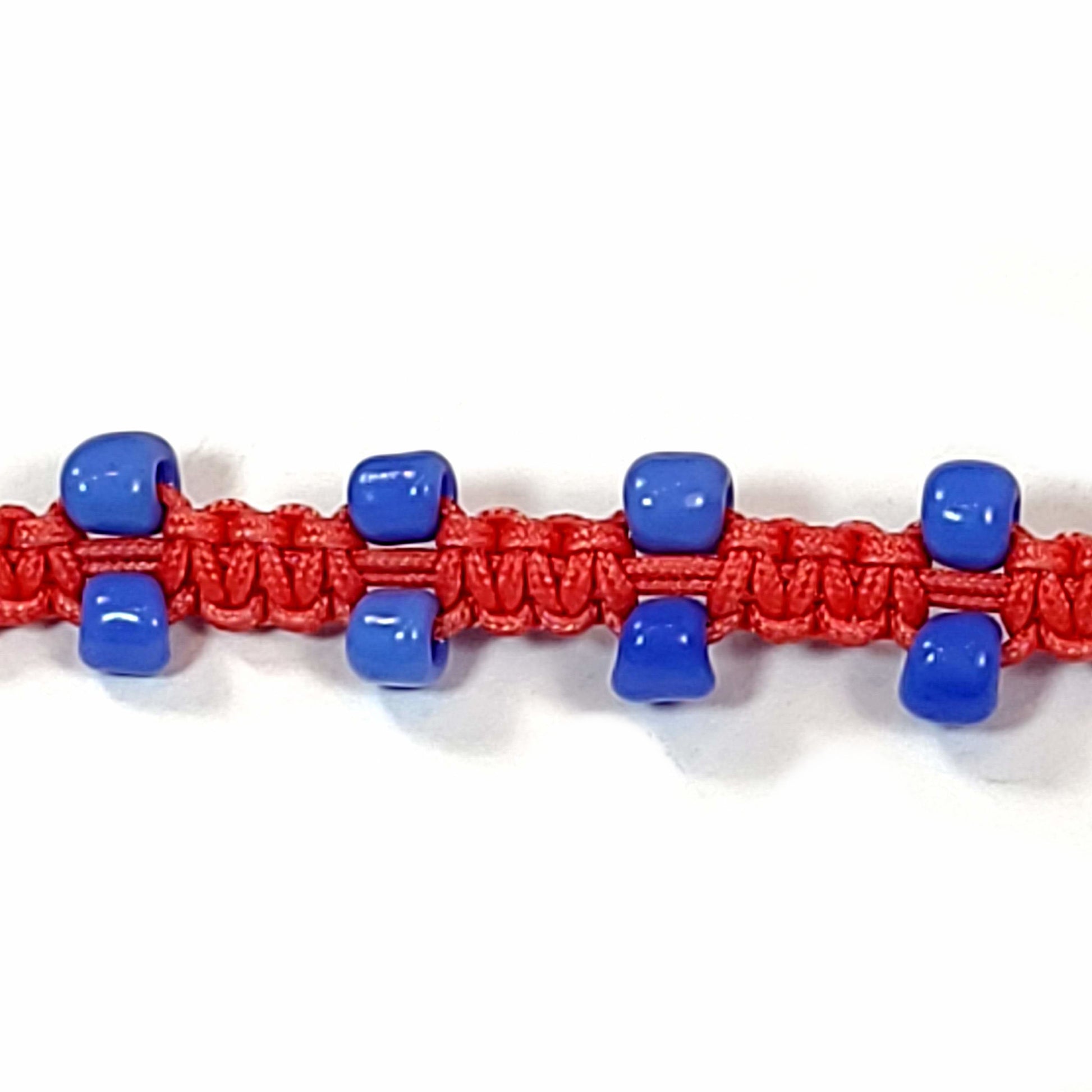 Close up of a bracelet made with red macrame cord and sky blue glass pony beads.