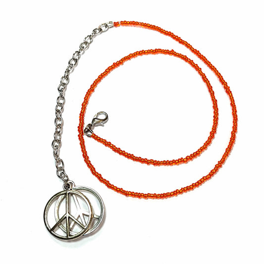 Single strand necklace made of orange seed beads with an extender that has 2 peace sign charms on the end.