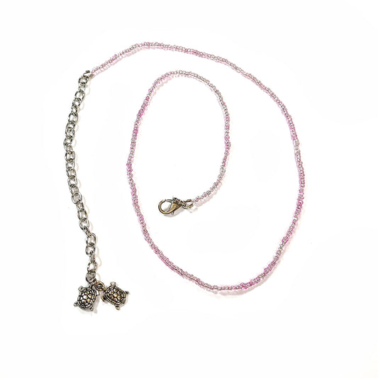 Single strand pink seed bead necklace with an extender that has 2 turtle charms on the end.