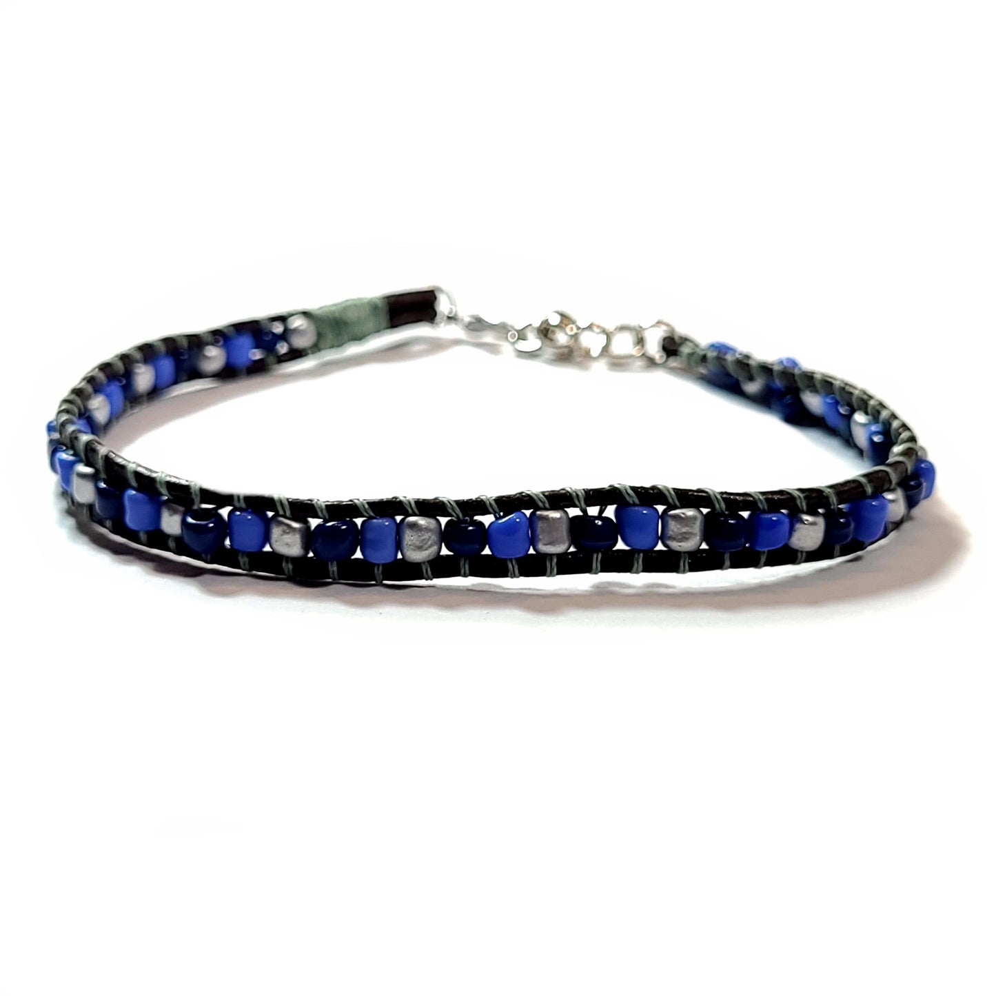 Light blue, dark blue, and gray beads flanked by brown leather, with greenish gray beading line bracelet.