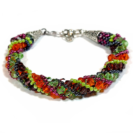 Bracelet made of green, orange, and purple bicone beads and light green, magenta, and black seed beads in a spiral pattern with silver color ends and lobster clasp.